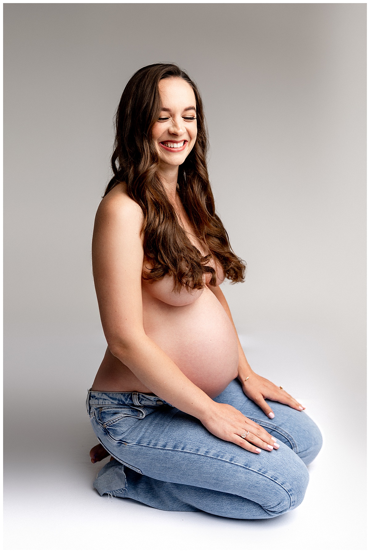 Woman kneels down smiling with pregnant belly for Virginia Maternity Photographer