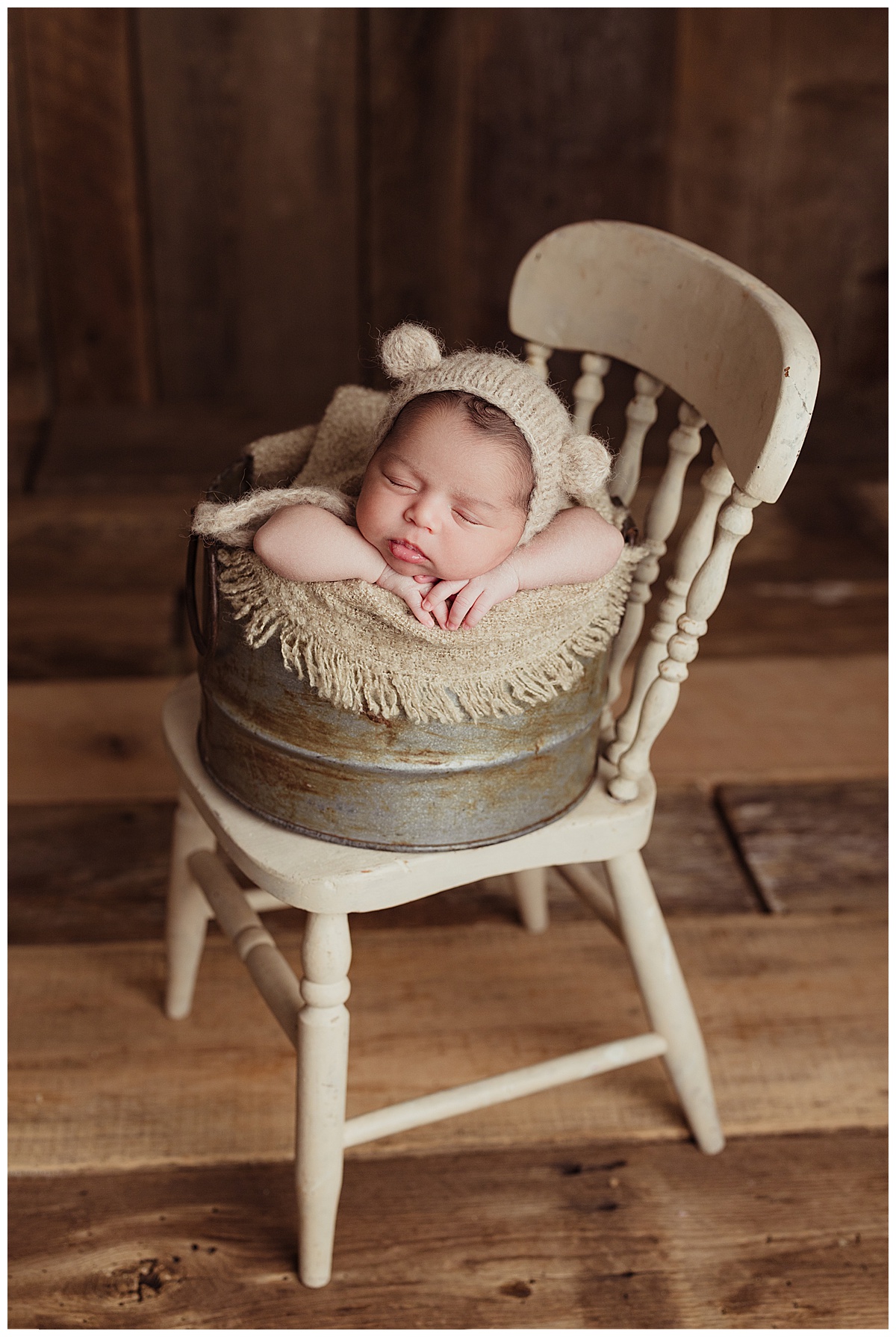 Tiny baby sits in basket on the chair for Norma Fayak Photography