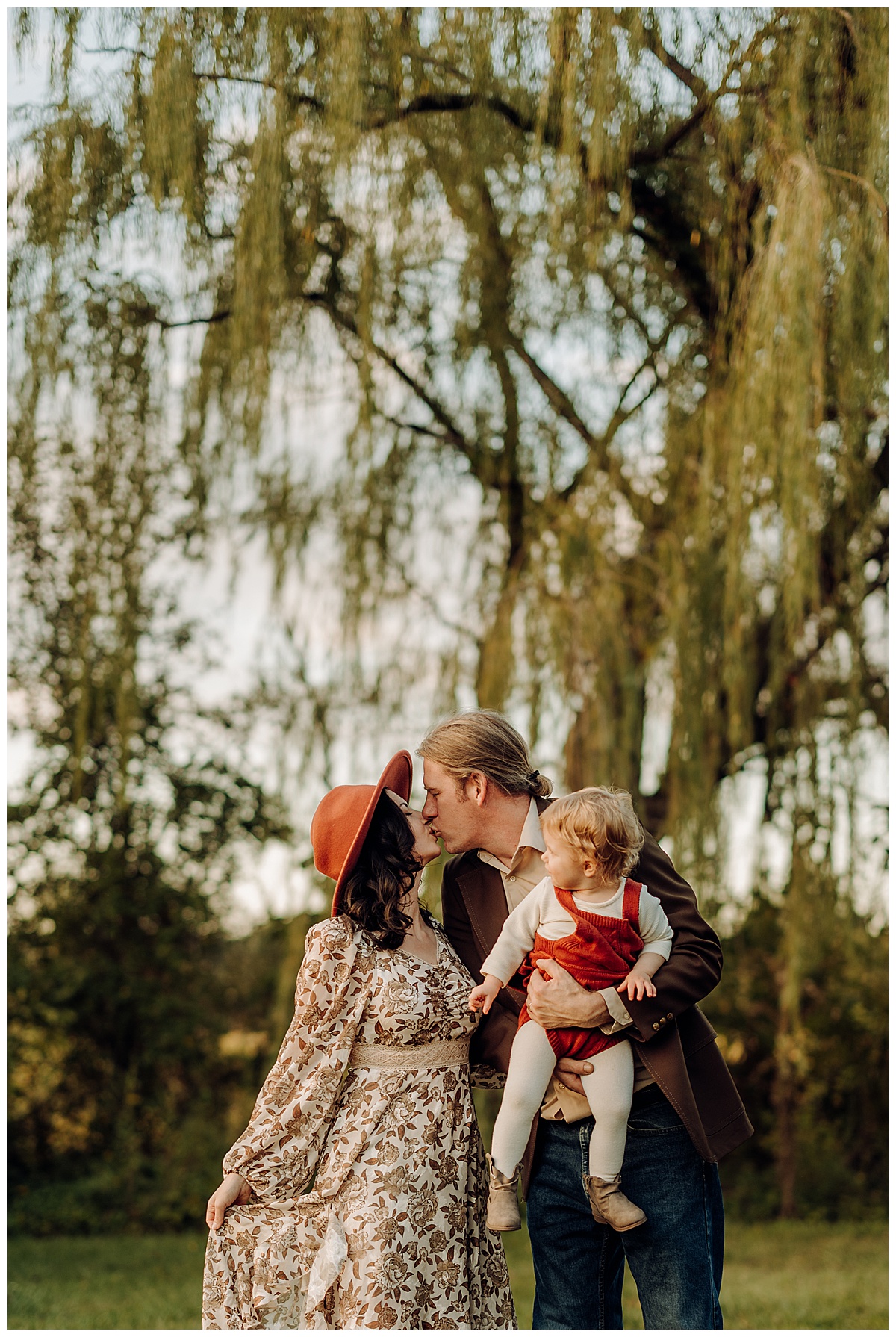 Parent share a kiss while holding their baby for Norma Fayak Photography