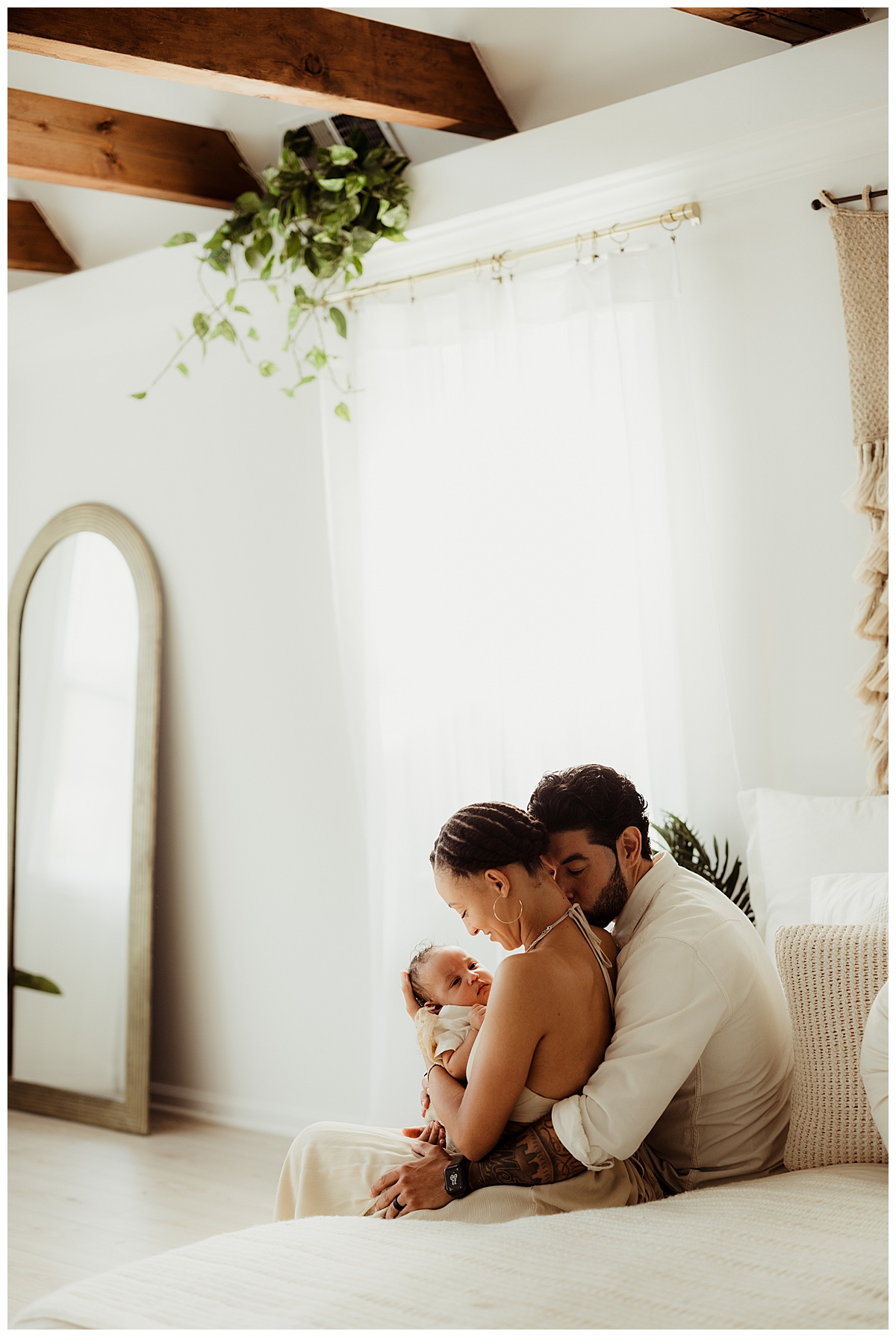 Parents sit on the bed with their baby for Norma Fayak Photography