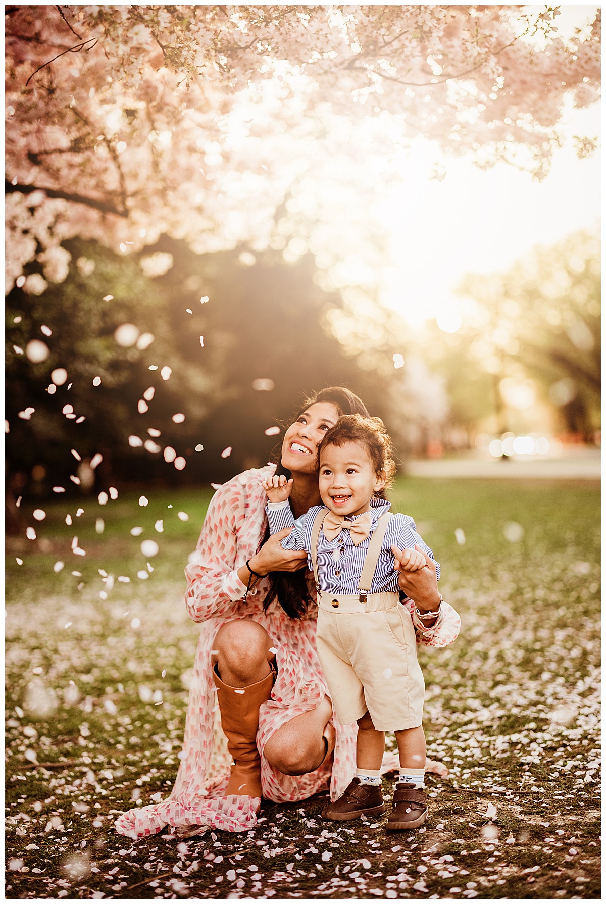 Mom and son play together in flower petals during their Washington, DC, Cherry Blossom photos