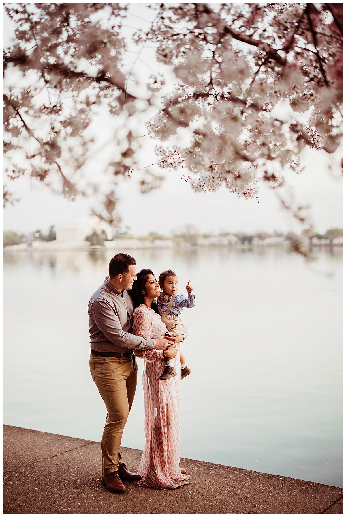 Mom and dad hold their son near the water during their DC Cherry Blossom Photographer