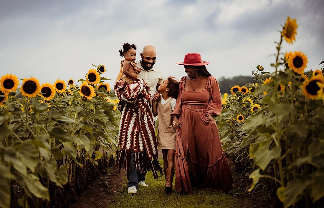 Family walks together in sunflower field for Norma Fayak Photography