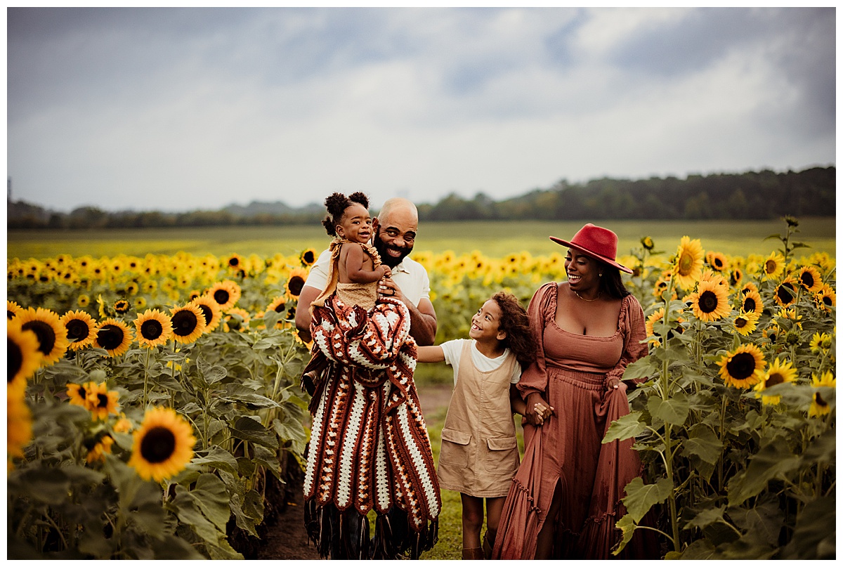 Family walks together smiling during their sunflower photoshoot