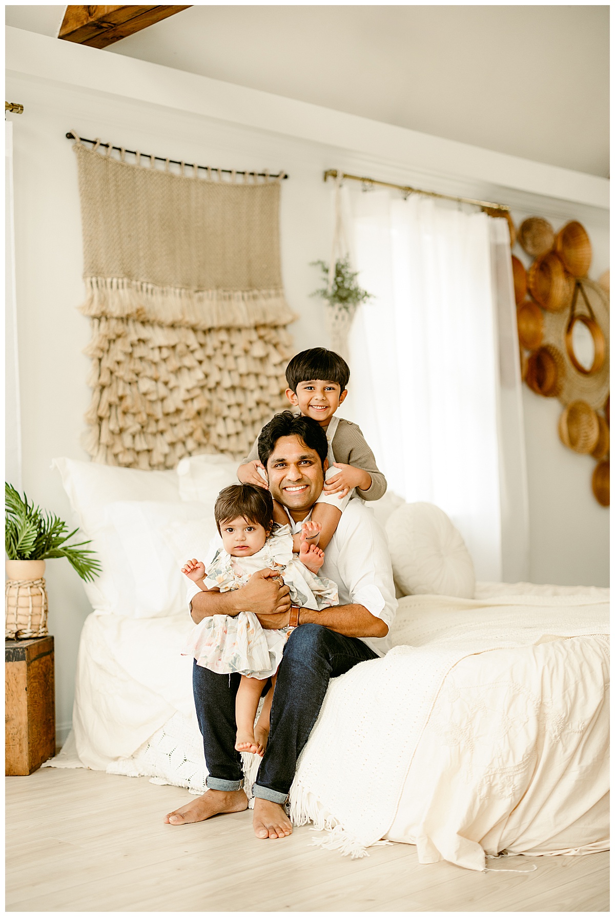 Dad sits with children on the bed during their Unposed Lifestyle Shoot