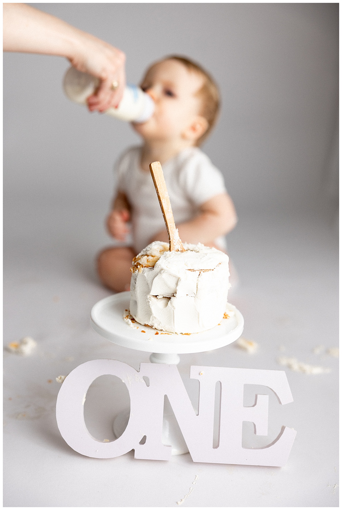 Baby drinks water while sitting next to a cake for Norma Fayak Photography
