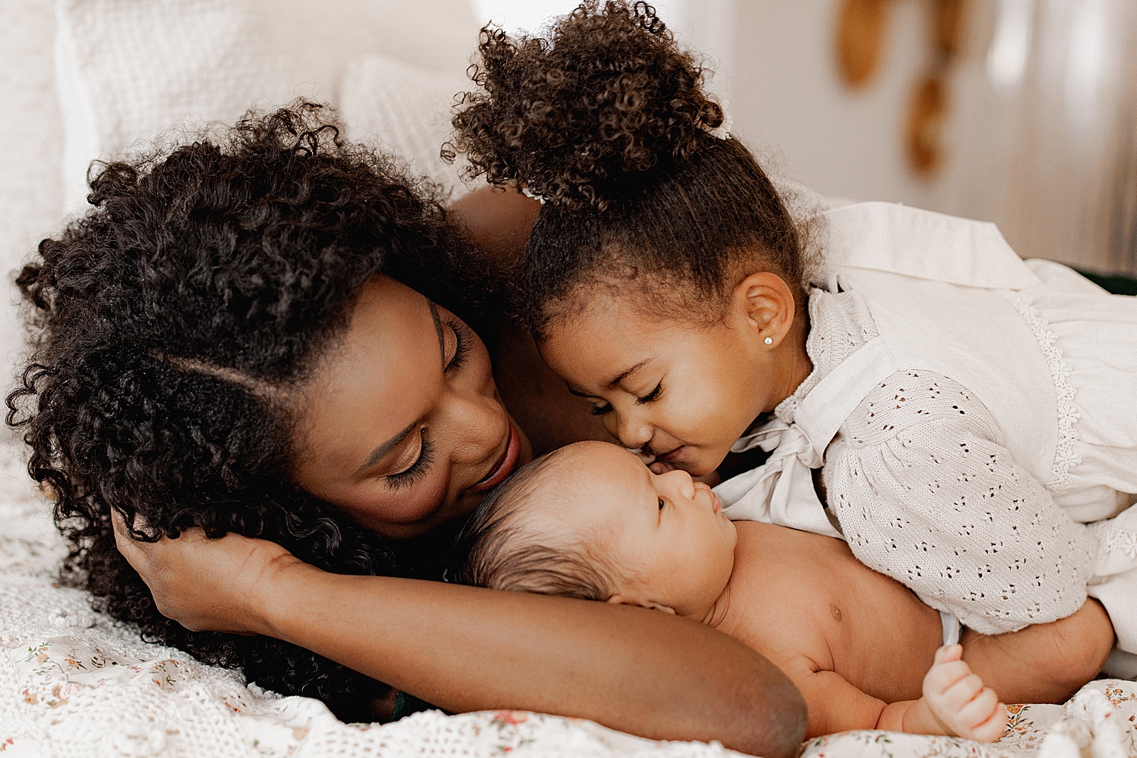 Mom and daughter kiss baby during Lifestyle Newborn Session