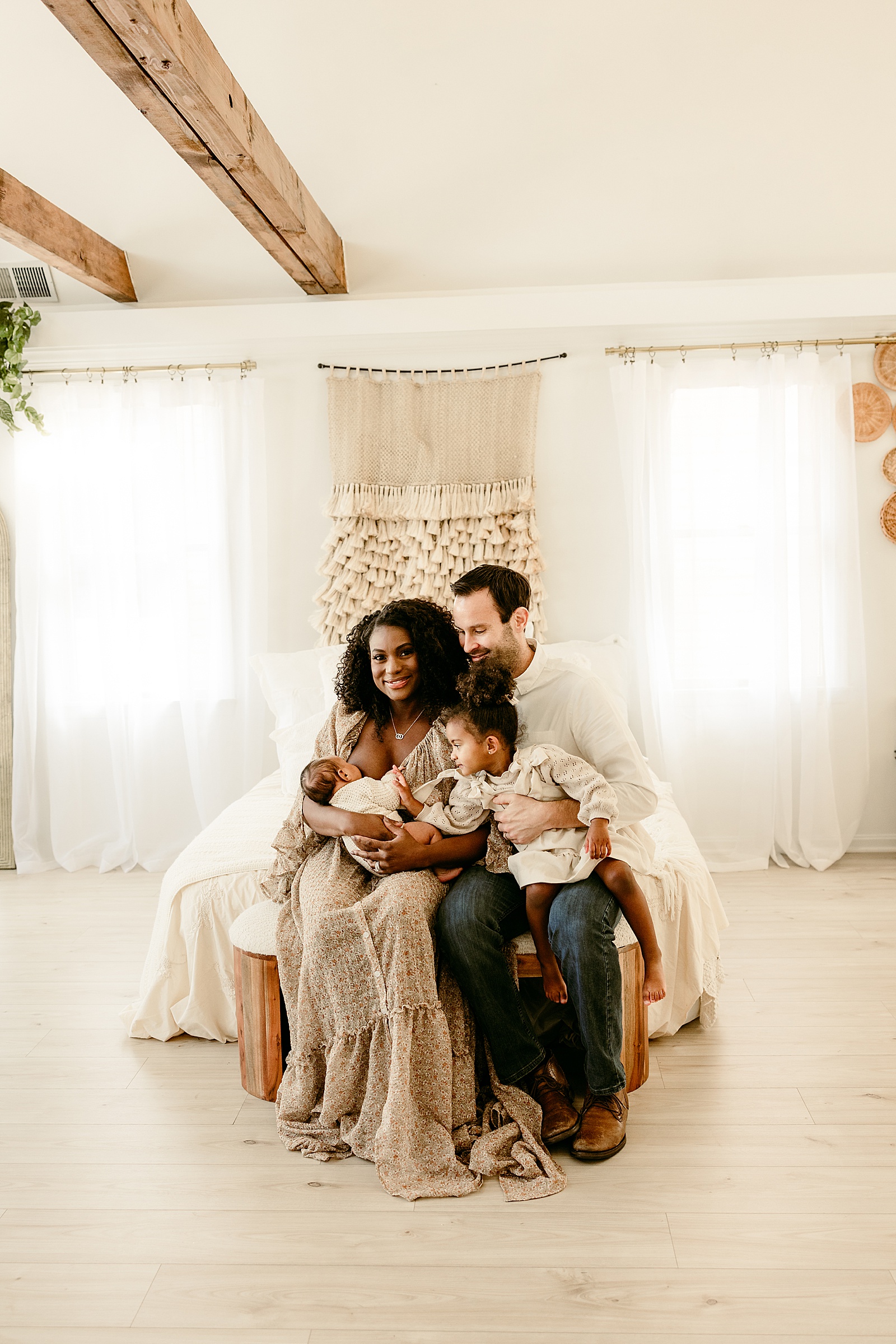 Family sits together on the bed during Lifestyle Newborn Session