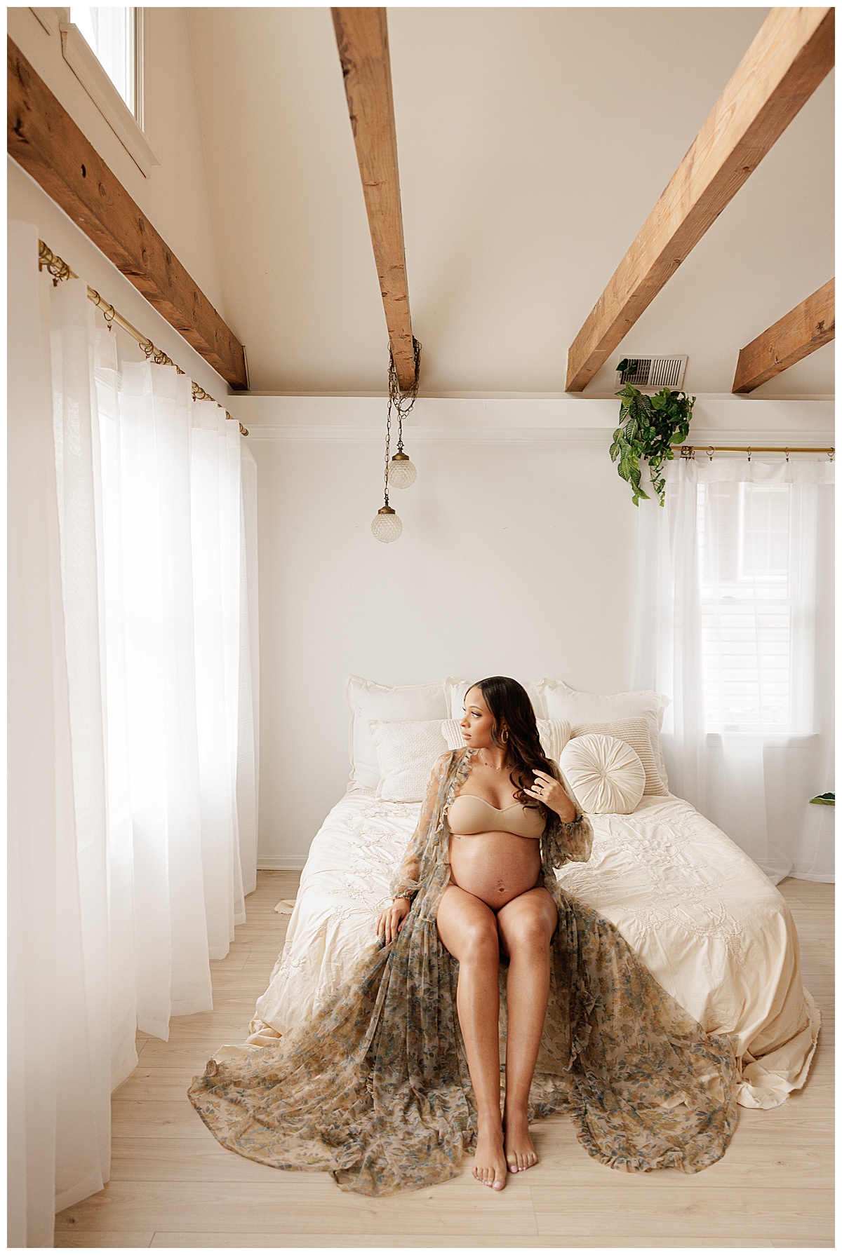 Woman sits on the edge of the bed showing off her baby bump for Virginia maternity photographer